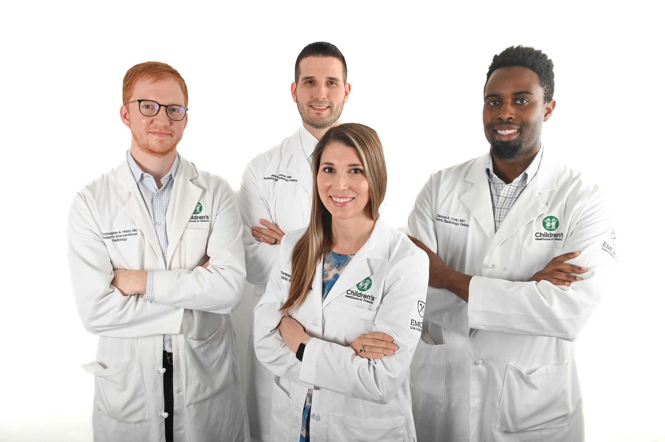 four people wearing white doctor coats and smiling with arms crossed