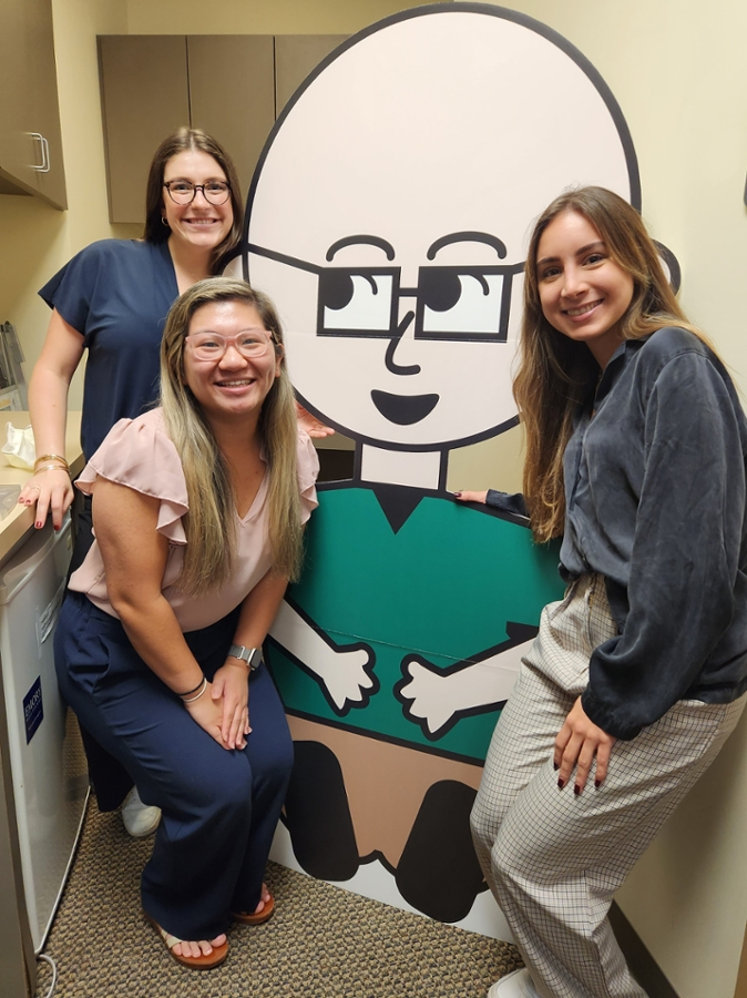 students posing with a large cutout of doctor cartoon