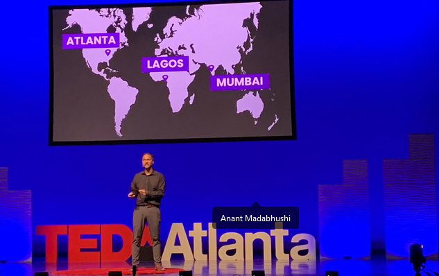 person standing on stage with TEDxAtlanta letters below them and a map behind them 
