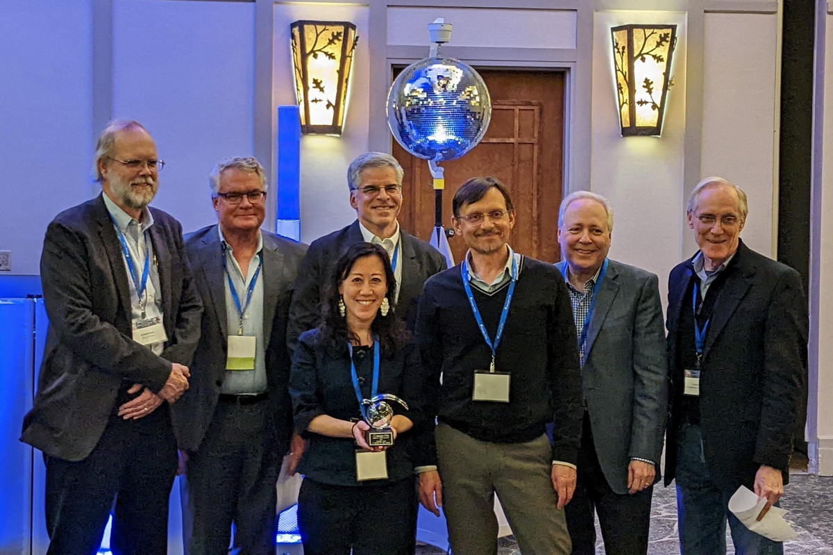 group of people standing around a person holding a crystal award