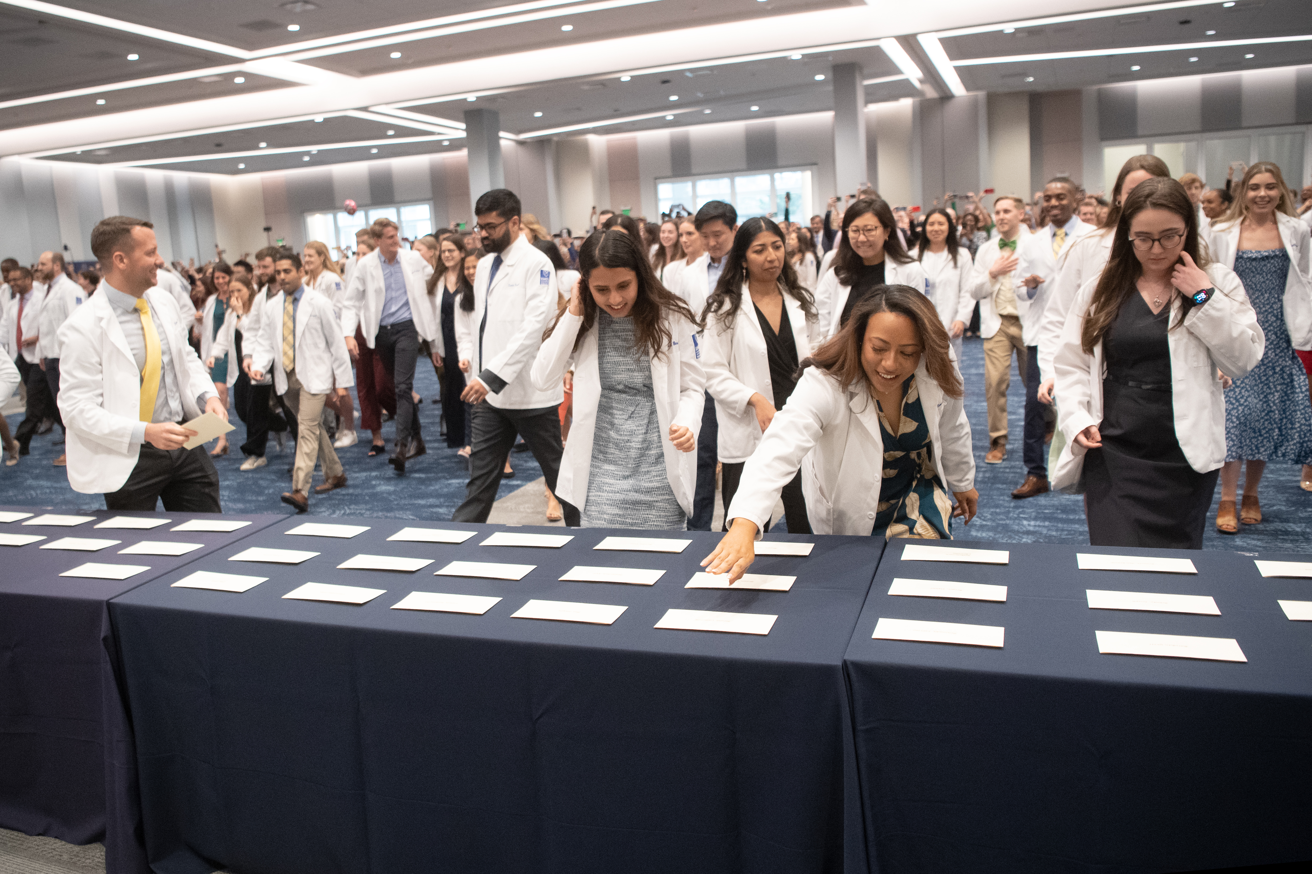students in white coats sitting in a full audience